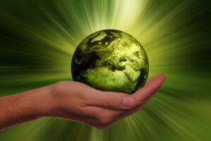 das Bild zeigt eine grüne Weltkugel in einer geöffneten Hand und symbolisiert so das System Nachhaltigkeit